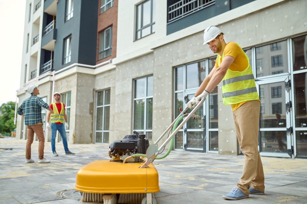 Worker cleaning construction site and two men near 2024 10 18 04 47 12 utc